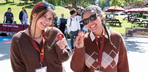 Two smiling RIC students holding up I love RIC pins