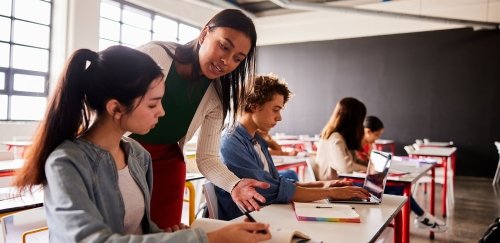 Teacher assistant helping student at table