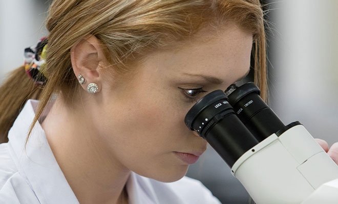 Person looking into microscope, biotechnology program
