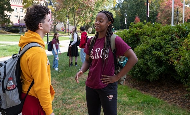 Students talking happily on the green, sunny campus