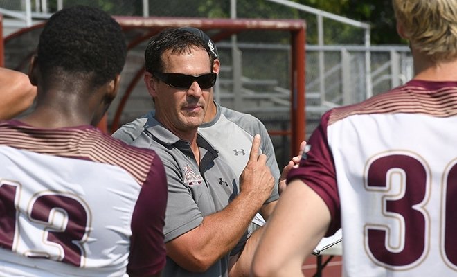 Coach on field with players circled around him