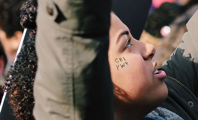Girl with girl power sticker on her face