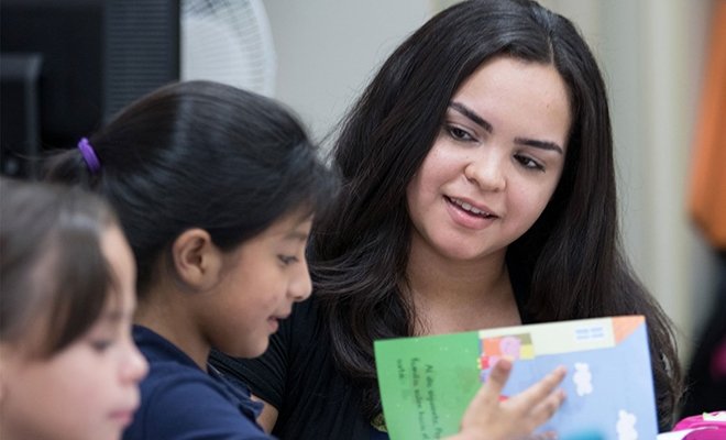 Student reading and working with elementary school students