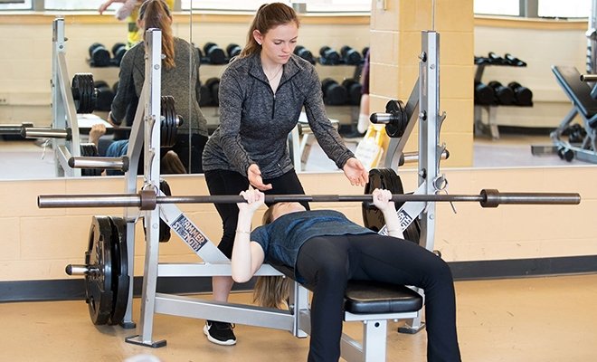 Student spotting another student lifting weights at the recreation center