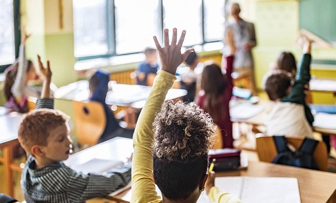 Young students raising their hands in class