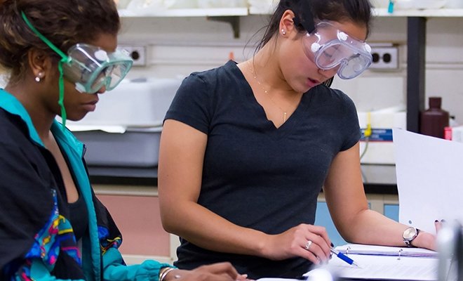 Two students working in lab with goggles on