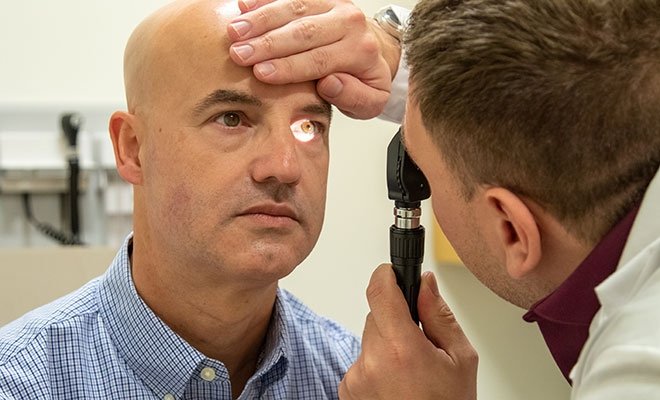 Graduate nursing student checking patient's eyes