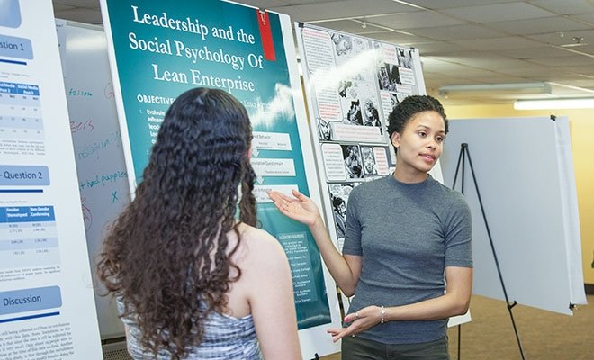 Student presenting in front of poster board on easel