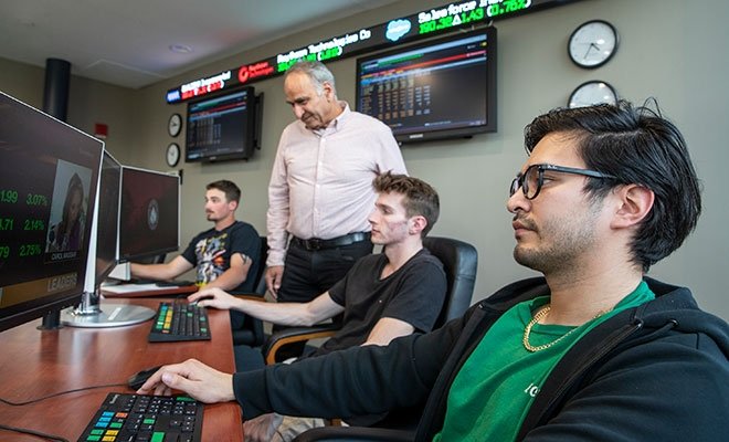 Students working with professor in RIC's finance lab