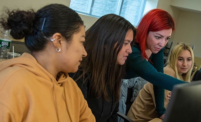 Students looking at monitor with professor in psychology class